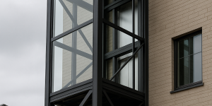 elevador exterior de vidrio con estructura metálica negra junto a edificio moderno
